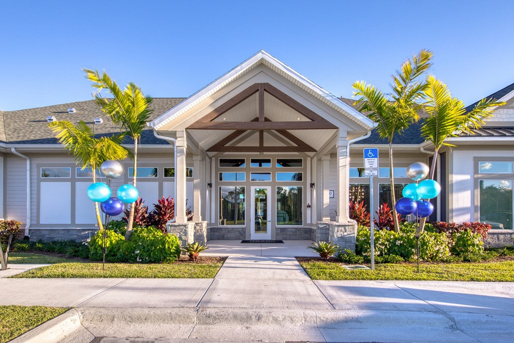 the front entrance of a building with palm trees and balloons