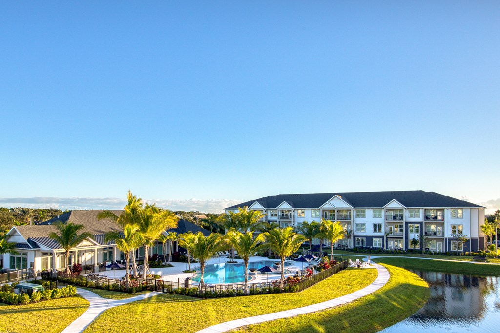an aerial view of a resort with a swimming pool and palm trees