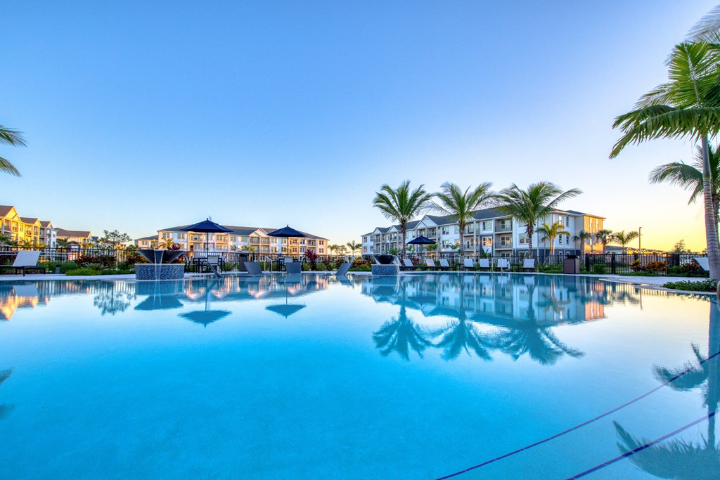 a large swimming pool with palm trees and buildings around it