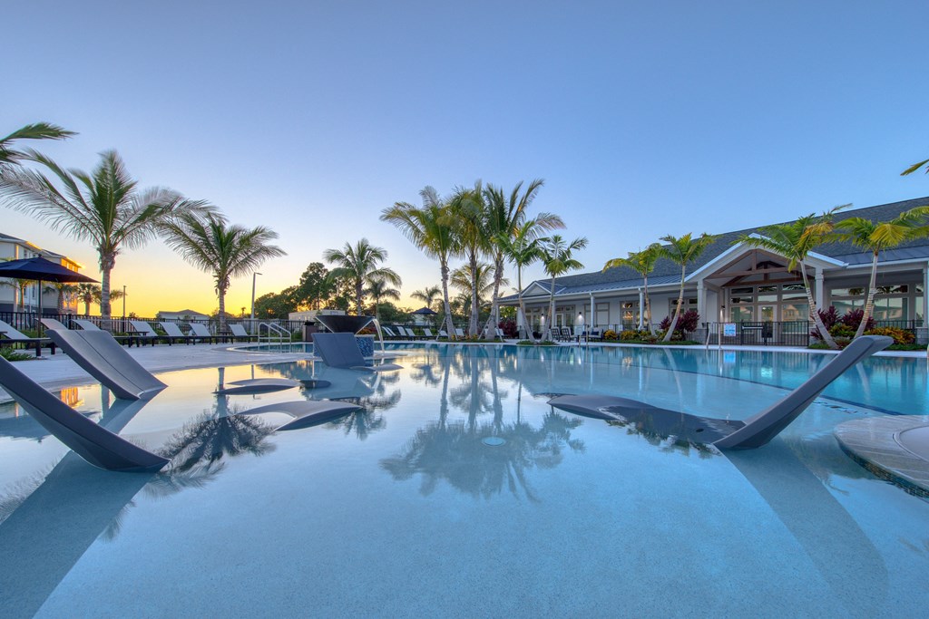 a large swimming pool with blue water and palm trees