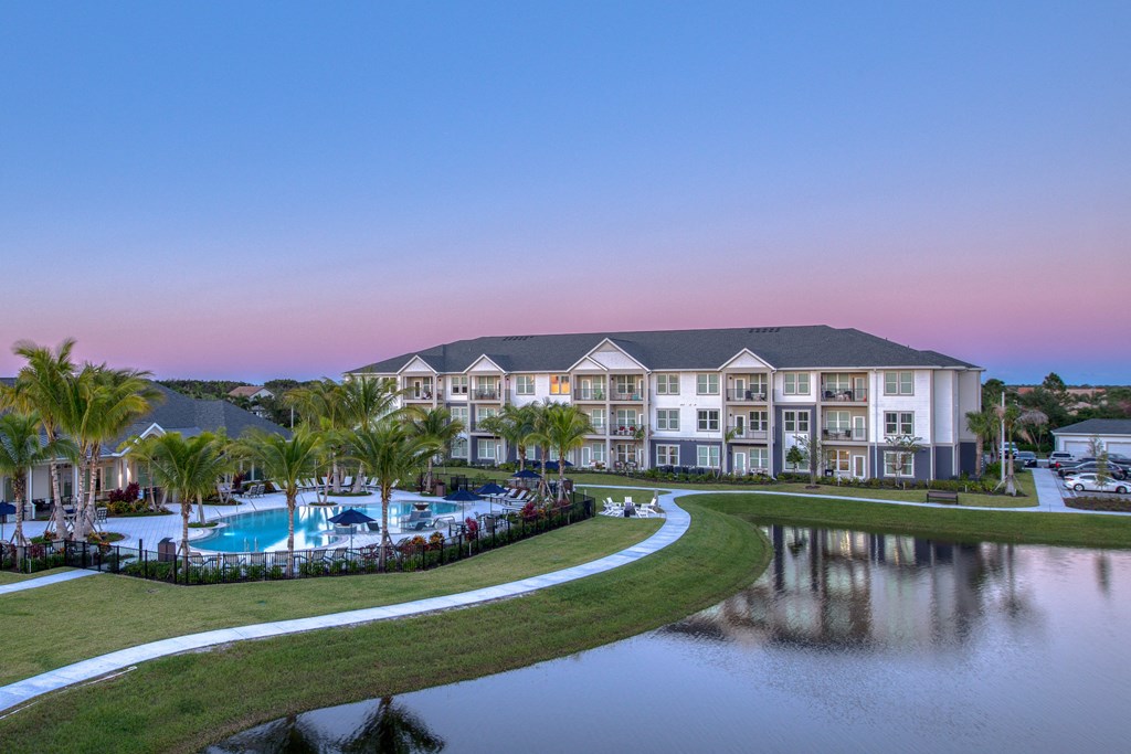 a large building with a pool and a lake at dusk