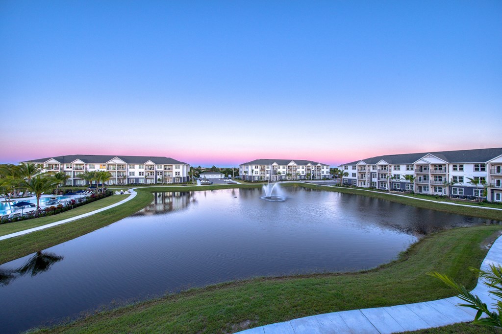 a fountain in the middle of a pond with houses around it