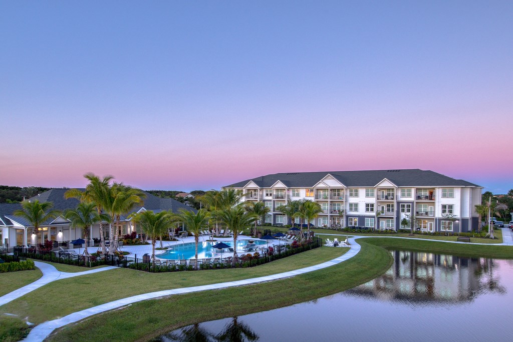 a large building with a pool and a lake at dusk