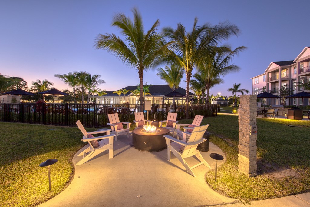 a patio with chairs and a fire pit at night