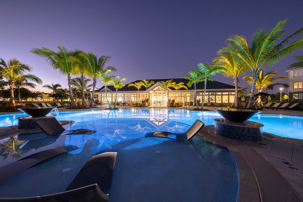 a large swimming pool at night with palm trees