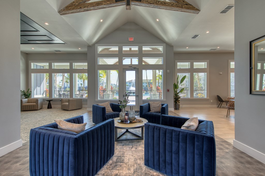 a large lobby with blue couches and chairs and windows