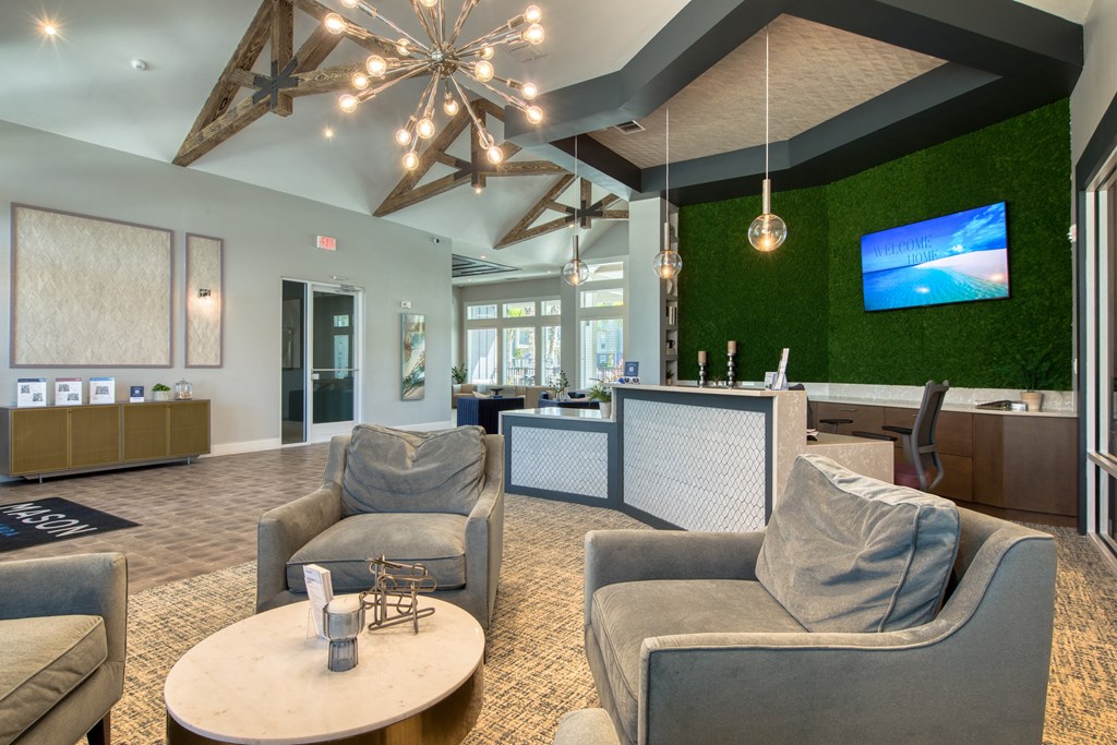 a lobby with couches and chairs and a reception area with a tv