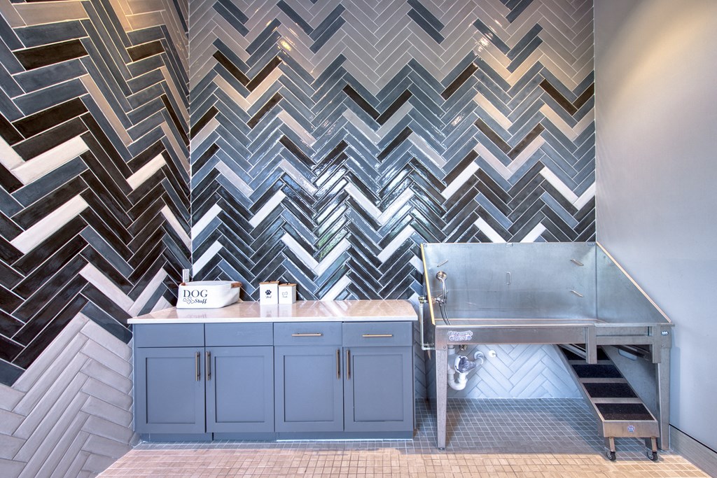 a kitchen with blue cabinets and a stainless steel sink and a checkered wall