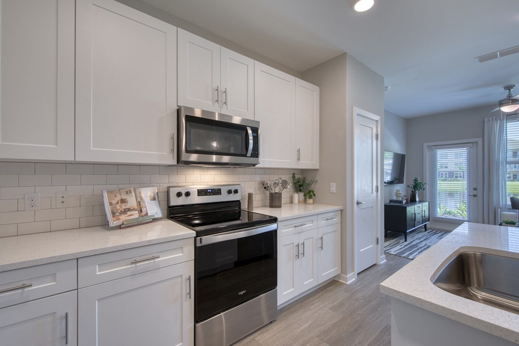 an open kitchen with white cabinets and a black stove and microwave