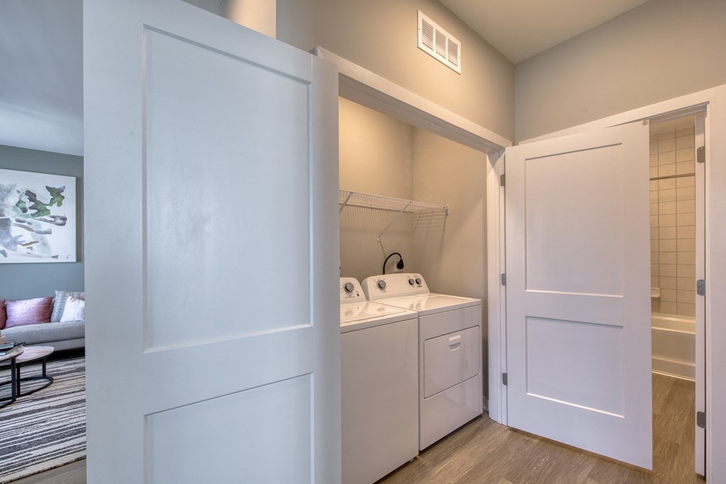 a laundry room with a washer and dryer and a door to a bathroom