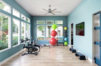 a home gym with ample windows and hardwood flooring