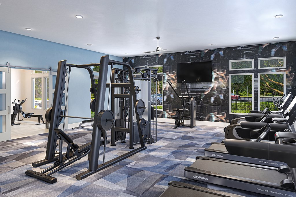 a gym with treadmills and weights in front of a wall with a tv