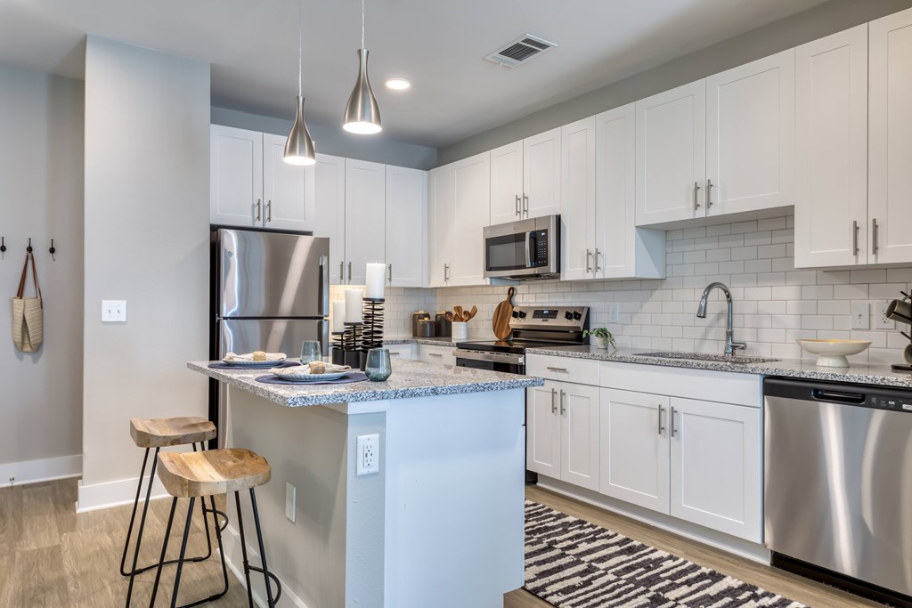 A kitchen with a white island and stainless steel appliances.