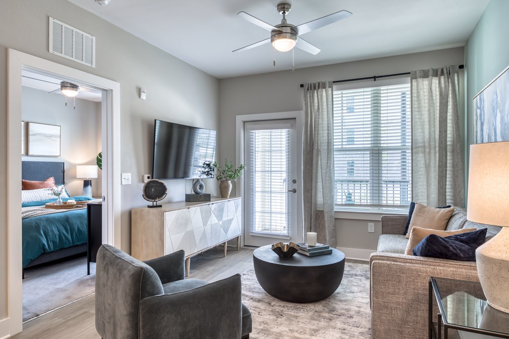 A living room with a grey couch, a black coffee table, and a ceiling fan.