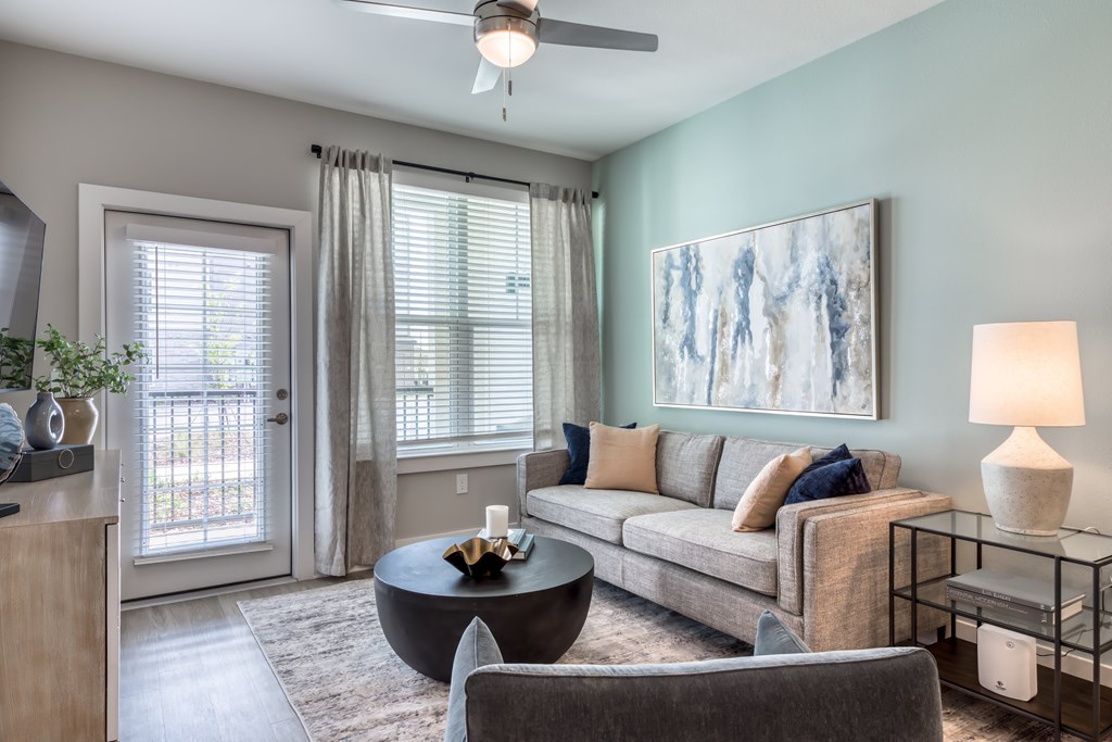 A living room with a grey couch, a coffee table, and a painting on the wall.