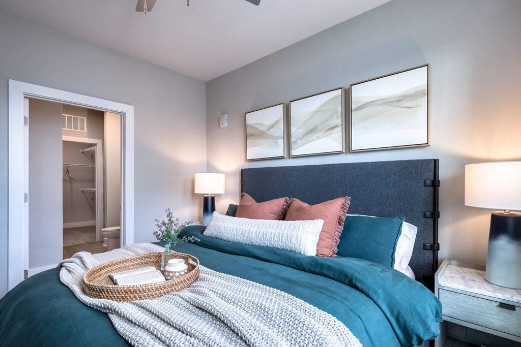 A bedroom with a bed, nightstand, and a painting on the wall.