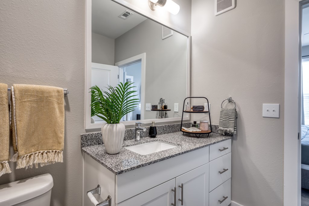 A bathroom with a white counter top and a large mirror.