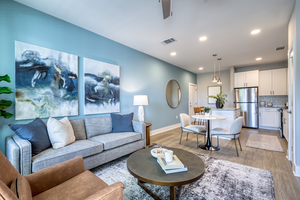 A living room with a grey couch, a coffee table, and a painting on the wall.