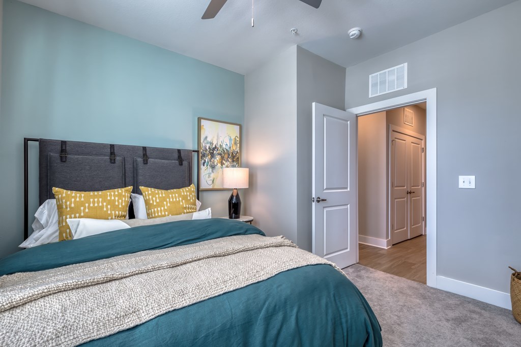 A bedroom with a bed, pillows, and a ceiling fan.