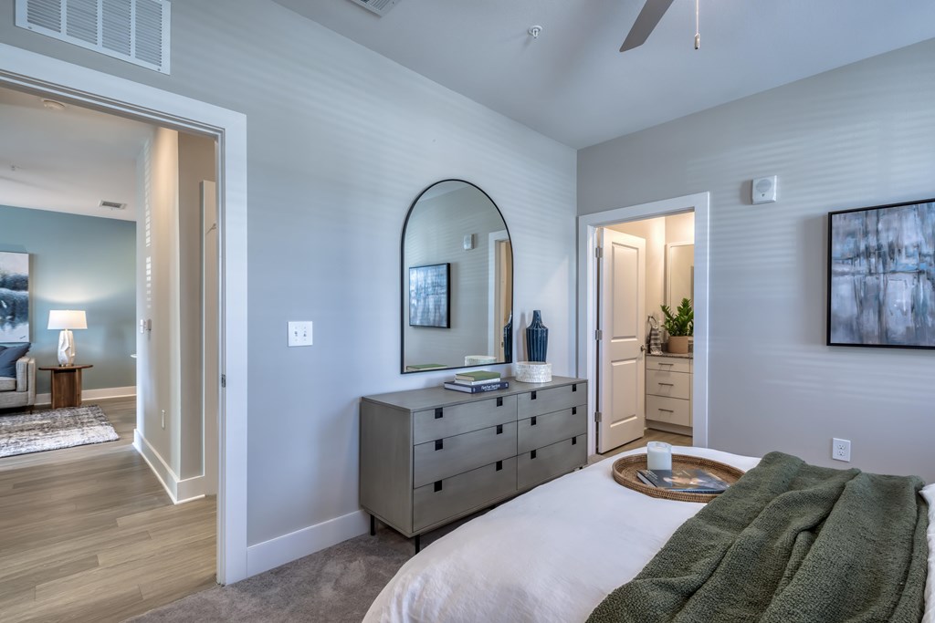 A bedroom with a large bed and a dresser with a mirror above it.