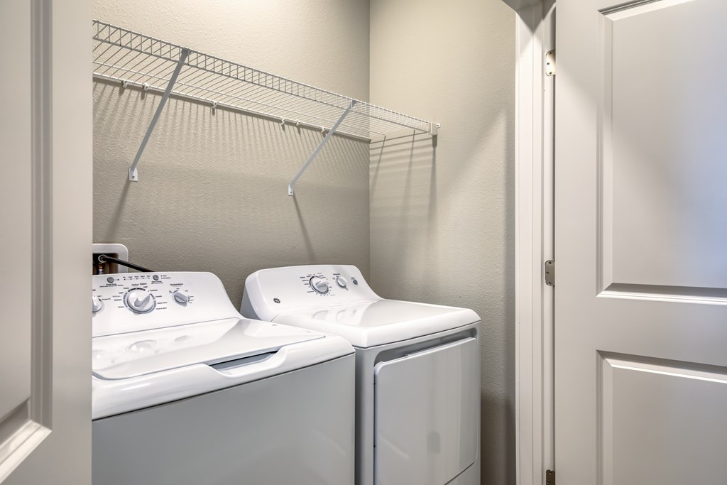 Two white washing machines in a laundry room.