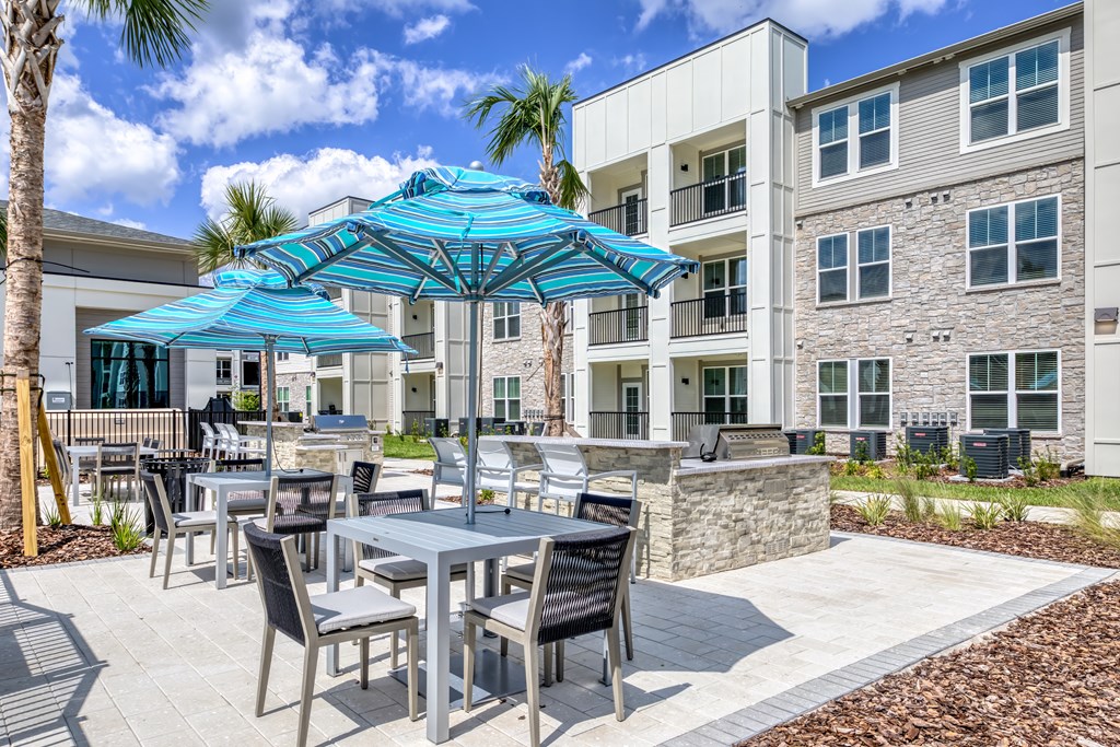 A patio with a table and chairs under a blue umbrella.