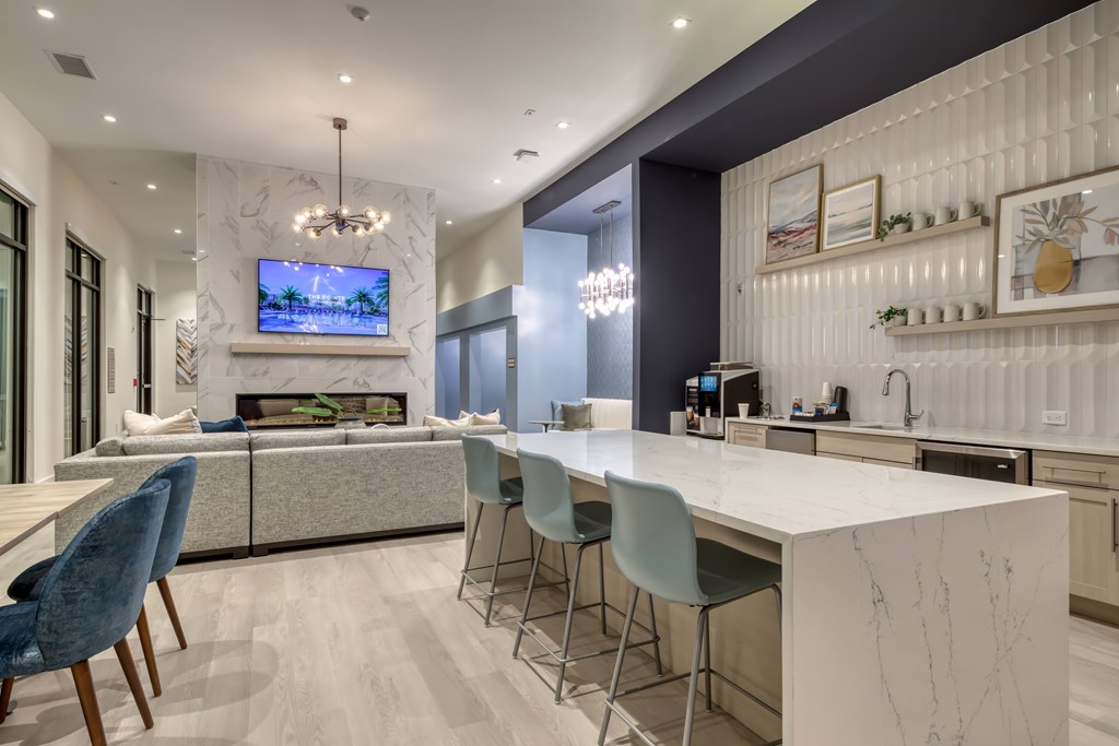 A modern kitchen with a white countertop and blue chairs.