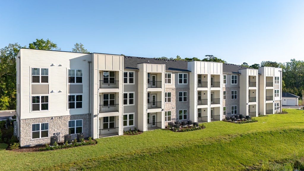 A row of modern apartment buildings with green lawns in front.