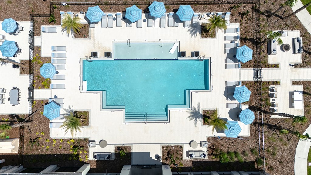 An aerial view of a swimming pool surrounded by lounge chairs and umbrellas.