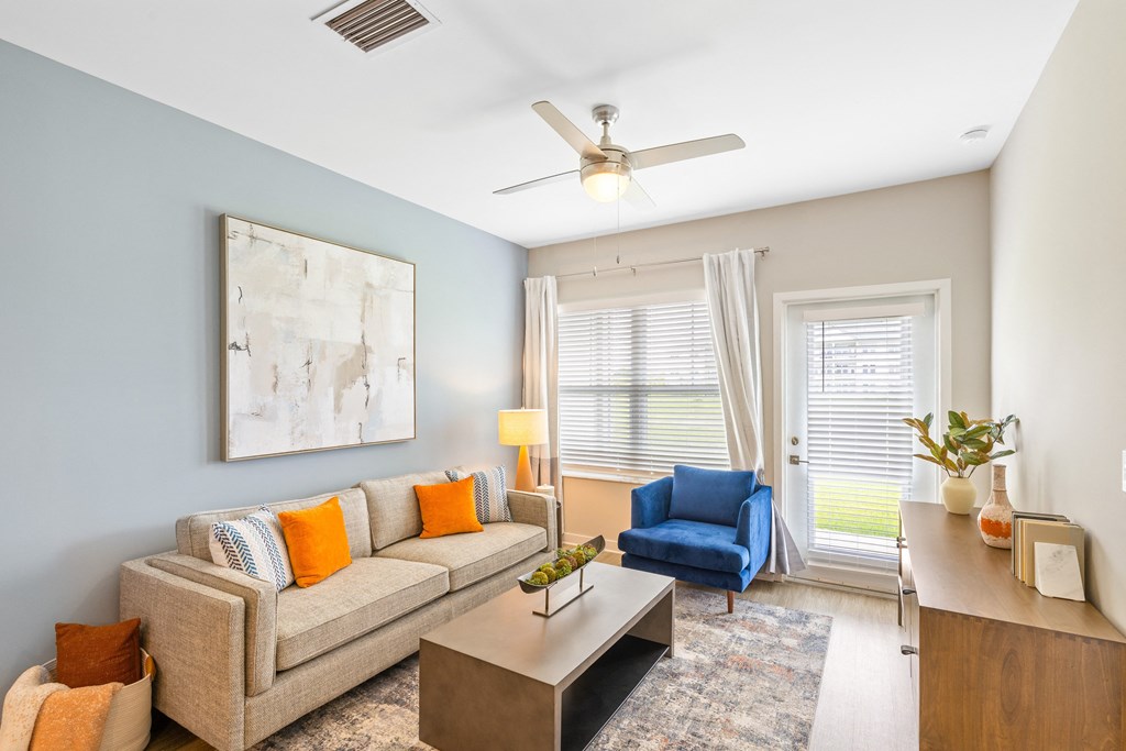 a living room with a couch and a chair and a ceiling fan