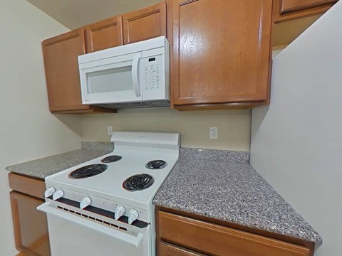 A white microwave oven is mounted above a stove in a kitchen.