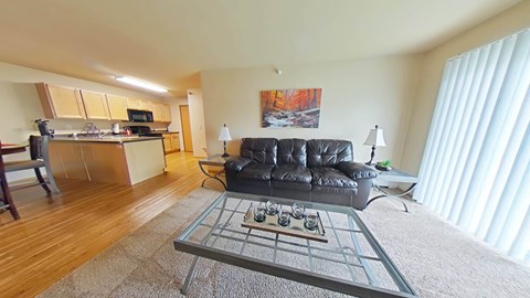 A living room with a black leather couch and a coffee table in the center.
