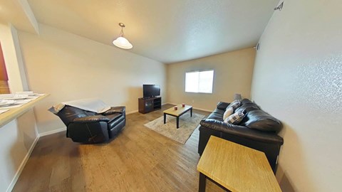 A living room with a black couch and a wooden table.