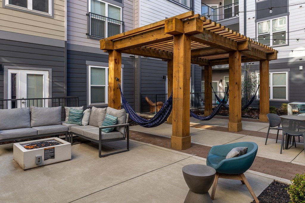 a patio with hammocks and couches in front of a house