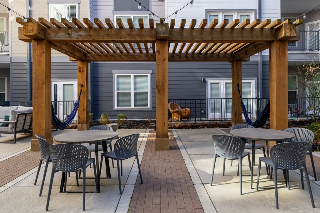 a patio with tables and chairs and a wooden pergola