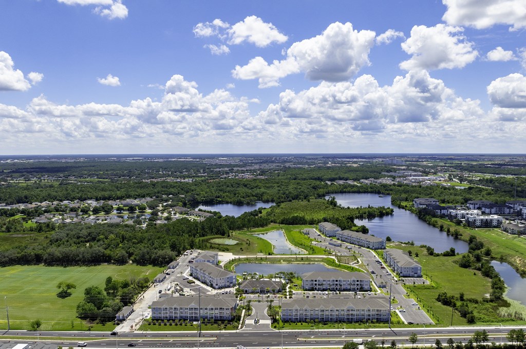 A large building complex sits in the middle of a green field with a river running through it.
