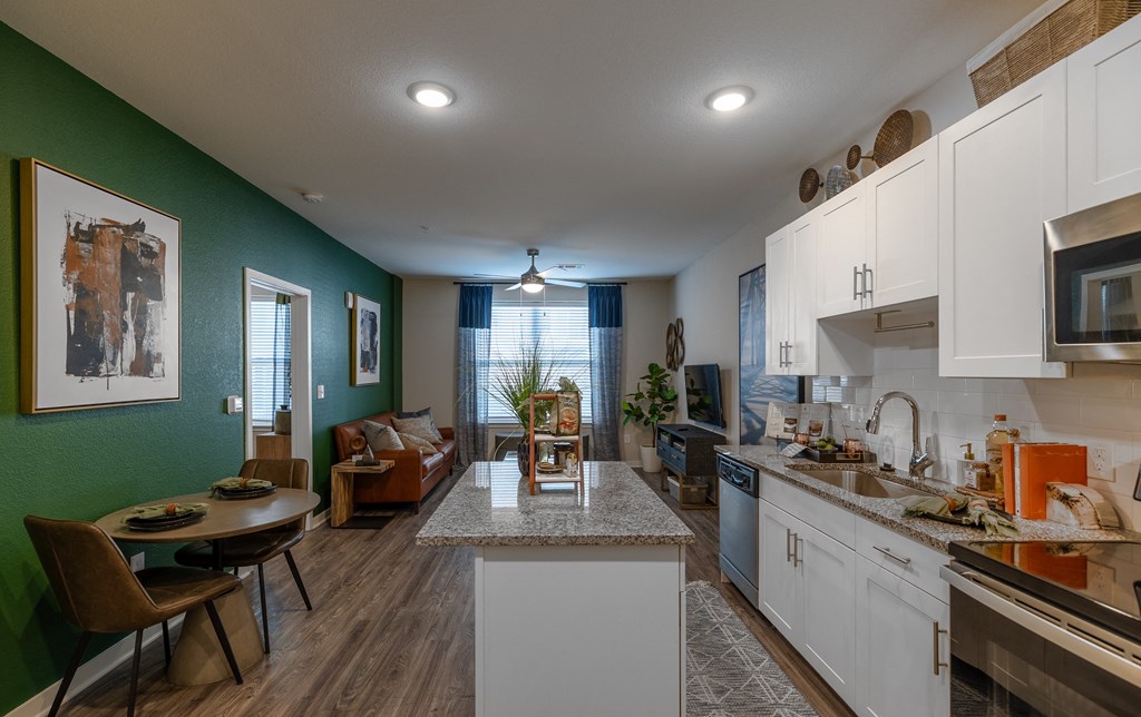 a kitchen and living room with green walls and white cabinets