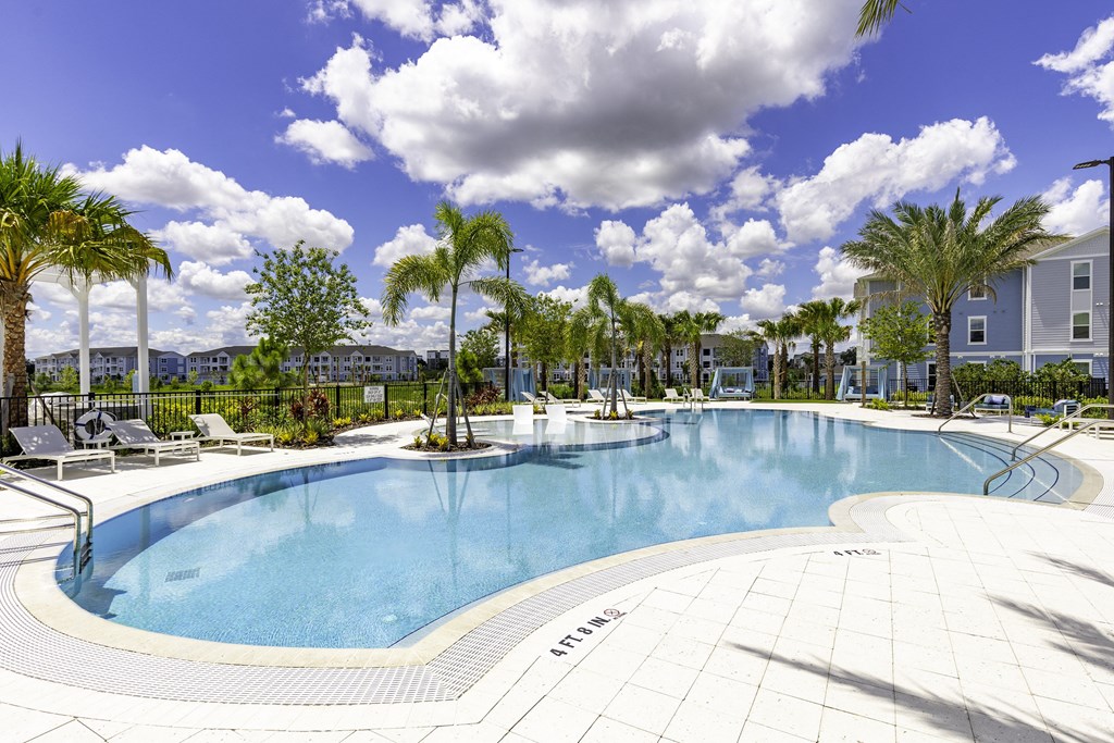 A large outdoor swimming pool surrounded by palm trees.