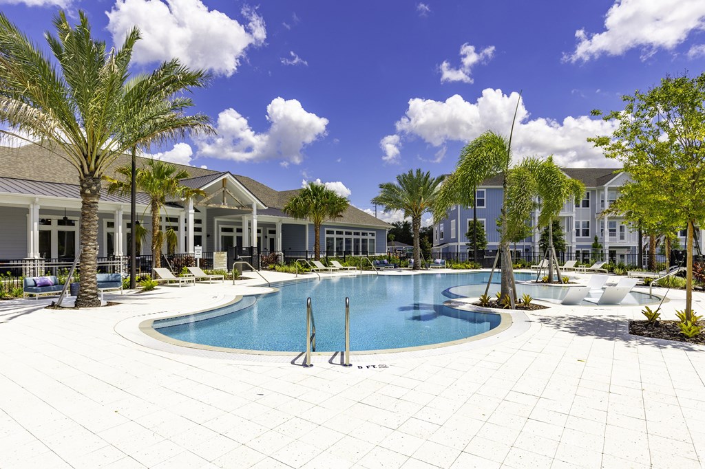 A swimming pool surrounded by palm trees and a white tiled patio.