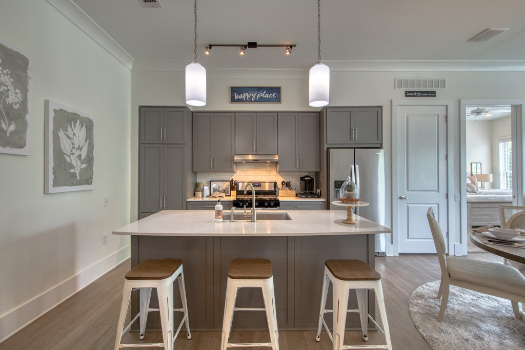 a kitchen with gray cabinets and a large island with three stools