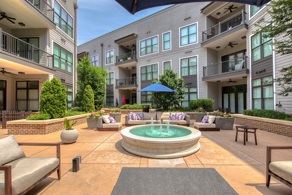 a fountain sits in the middle of a patio with furniture