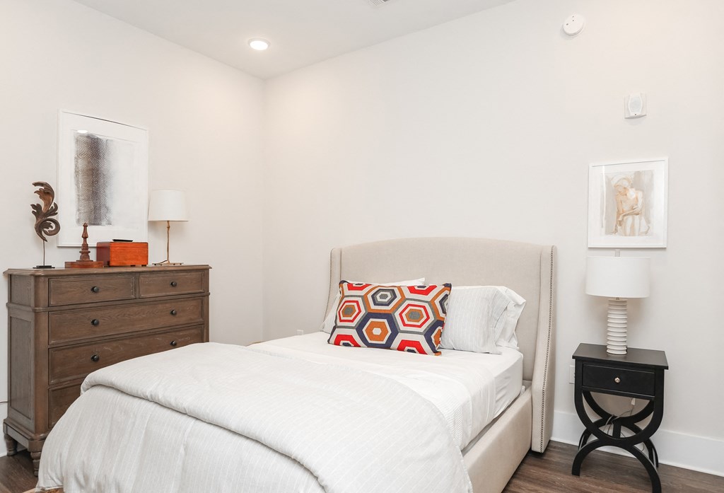 a bedroom with a white bed and a dresser and a window