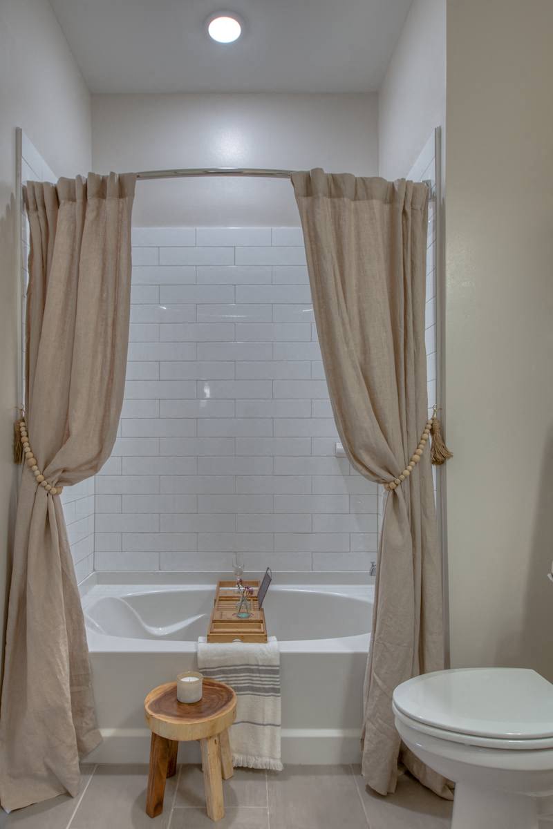 a bathroom with a tub and a toilet and a shower curtain