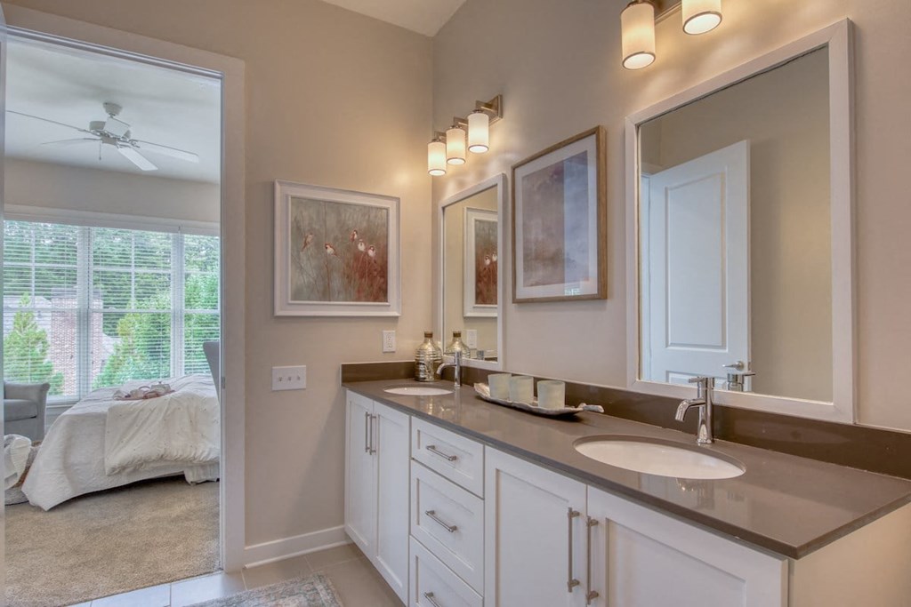a bathroom with two sinks and a mirror and a bedroom