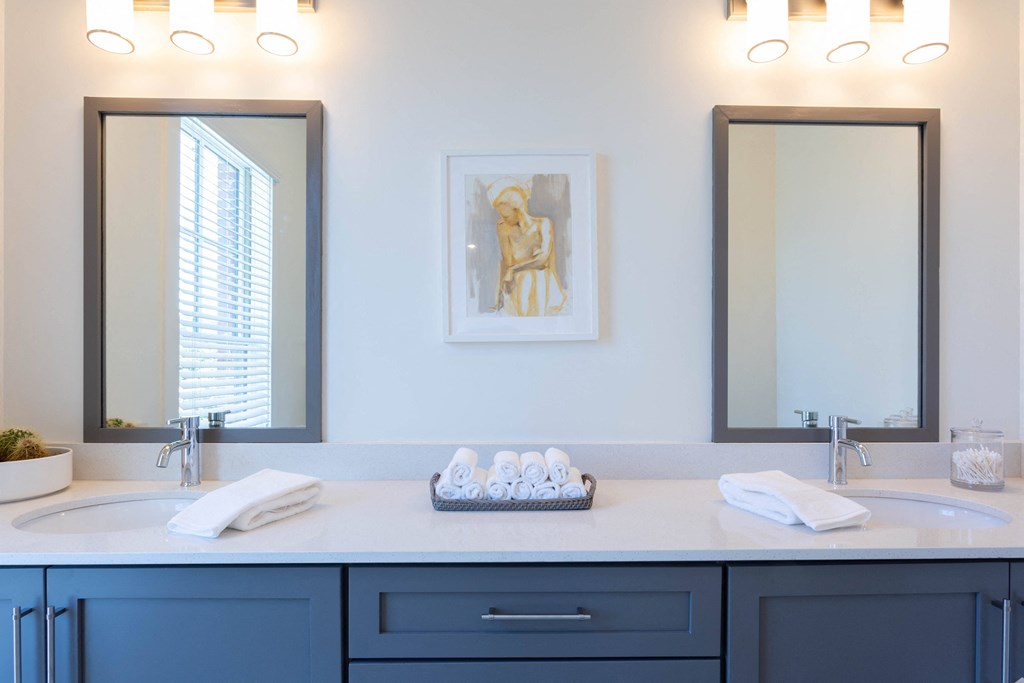 a blue and white bathroom with two sinks and two mirrors