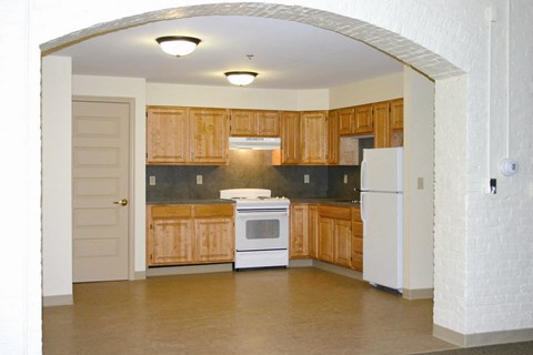 an empty kitchen with wooden cabinets and a white stove and refrigerator