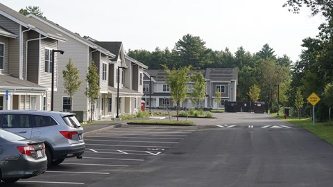 A parking lot in front of a residential area with cars parked.