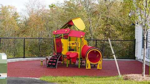 A playground with a red and yellow slide.