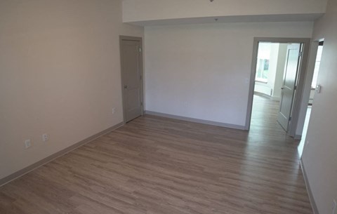an empty living room with wooden floors and white walls