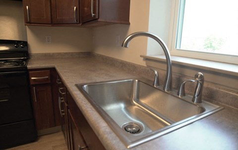 a stainless steel sink in a kitchen next to a window